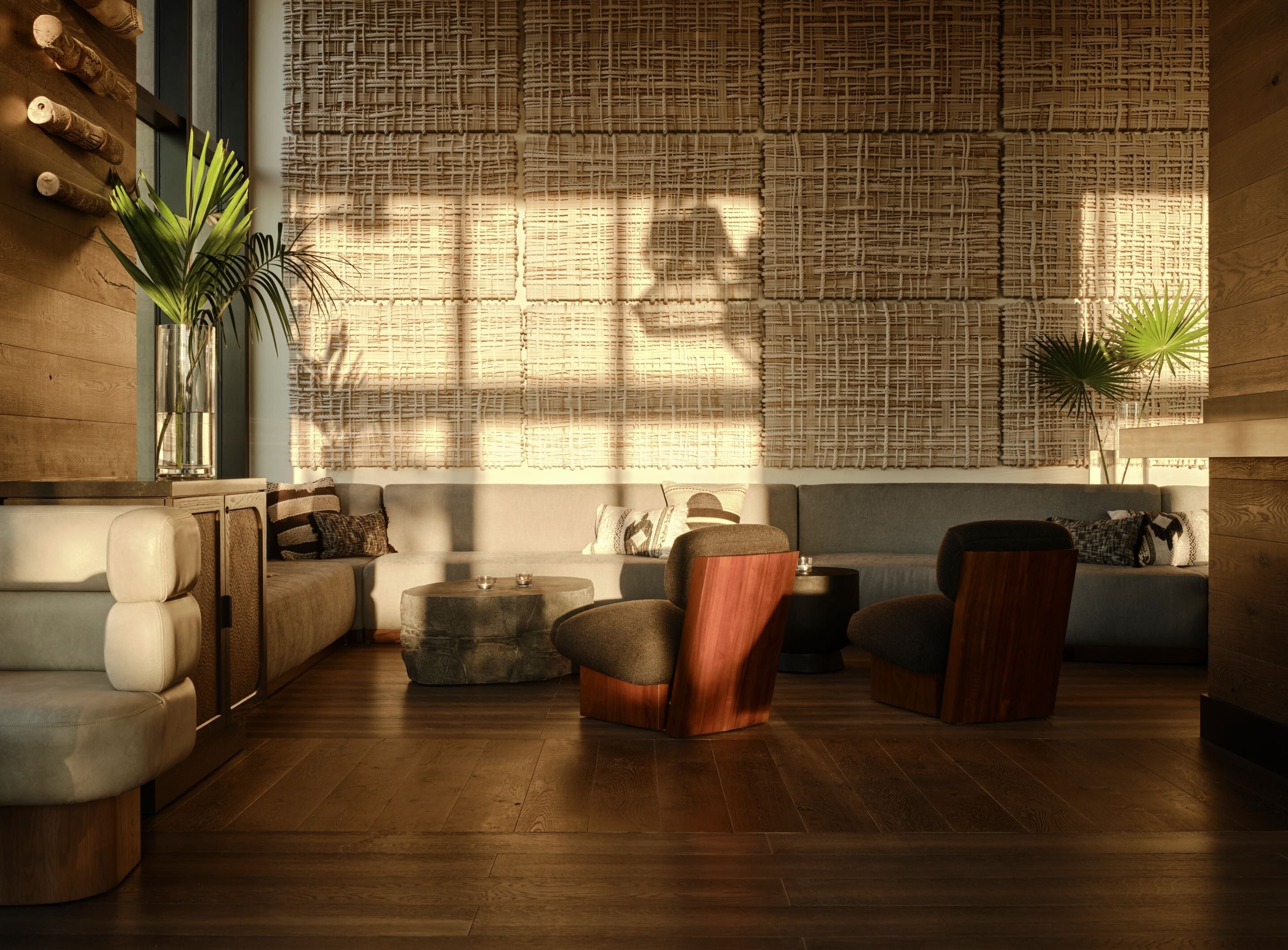Una sala de estar moderna con un sofá, sillones, una mesa de centro y una pared con textura tejida.