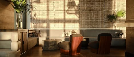 A modern living room with a sofa, armchairs, a coffee table, and a wall with a woven pattern.