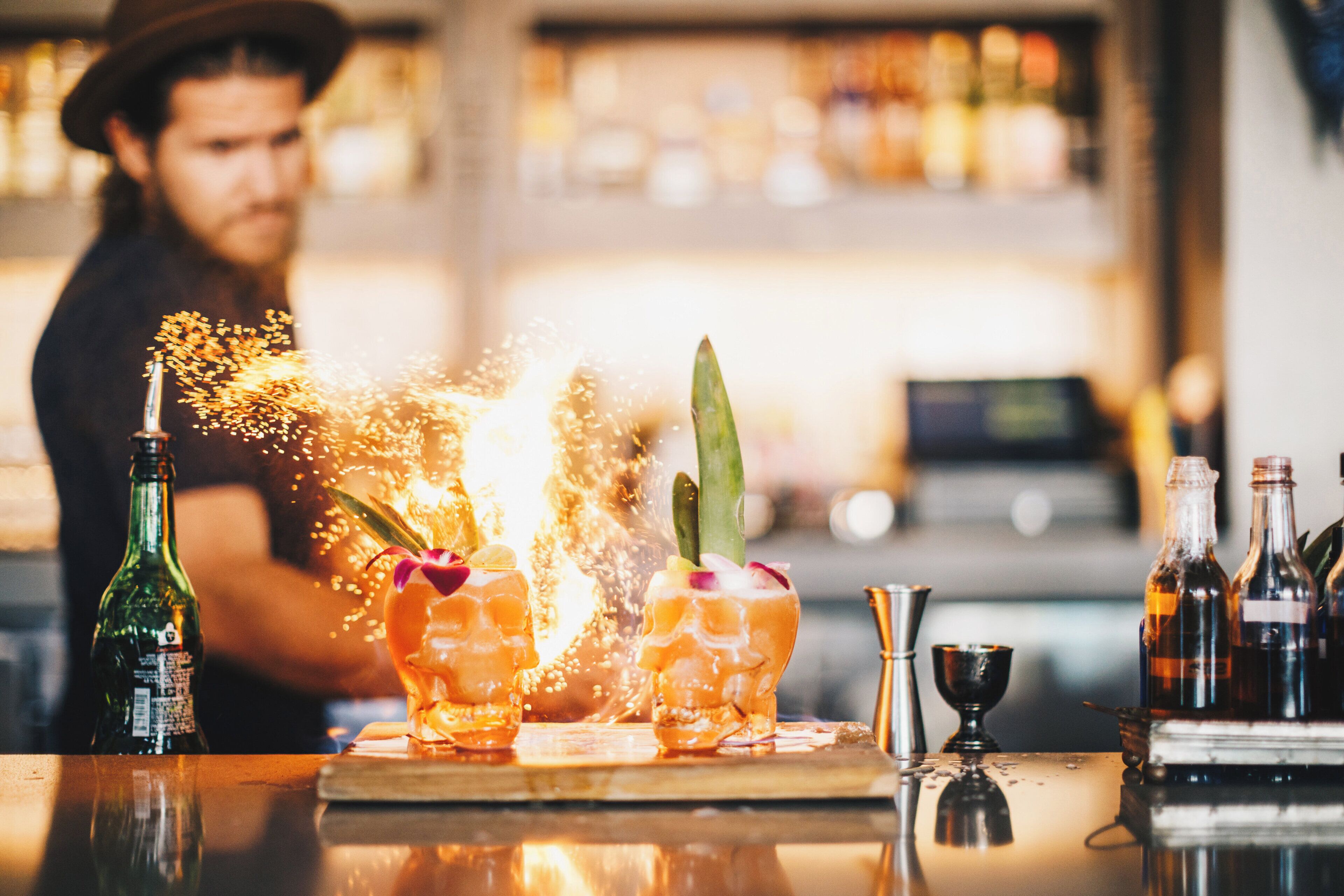 A bar setting with a bartender preparing drinks, a bottle of beer, and a variety of bar tools.