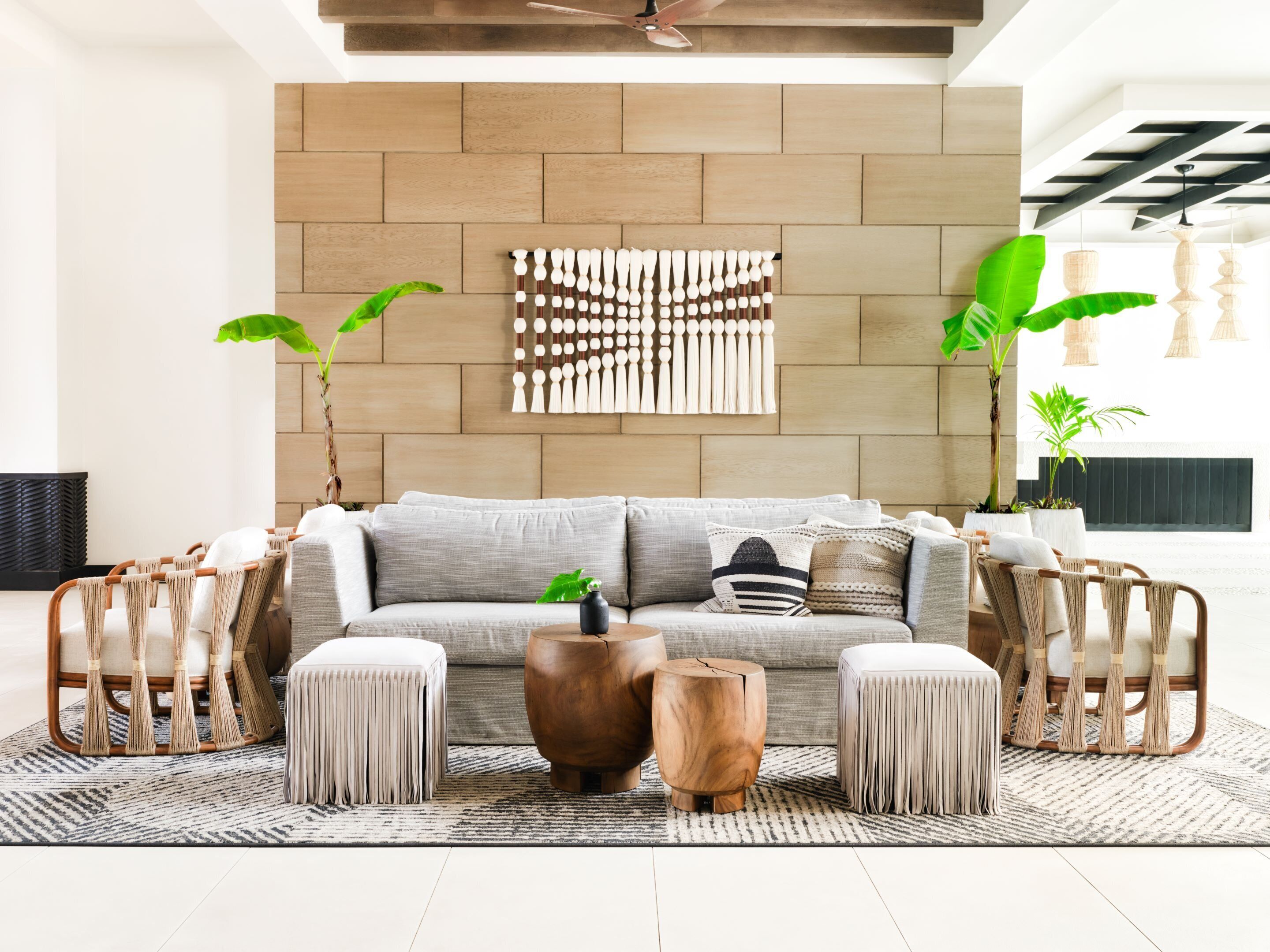 A modern living room with a grey sofa, wooden side tables, and a geometric wall art piece.