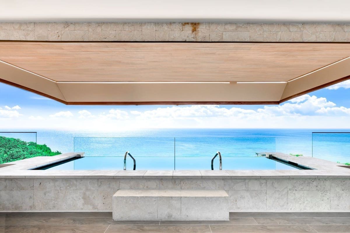 A modern infinity pool with a clear view of the ocean and a wooden ceiling.