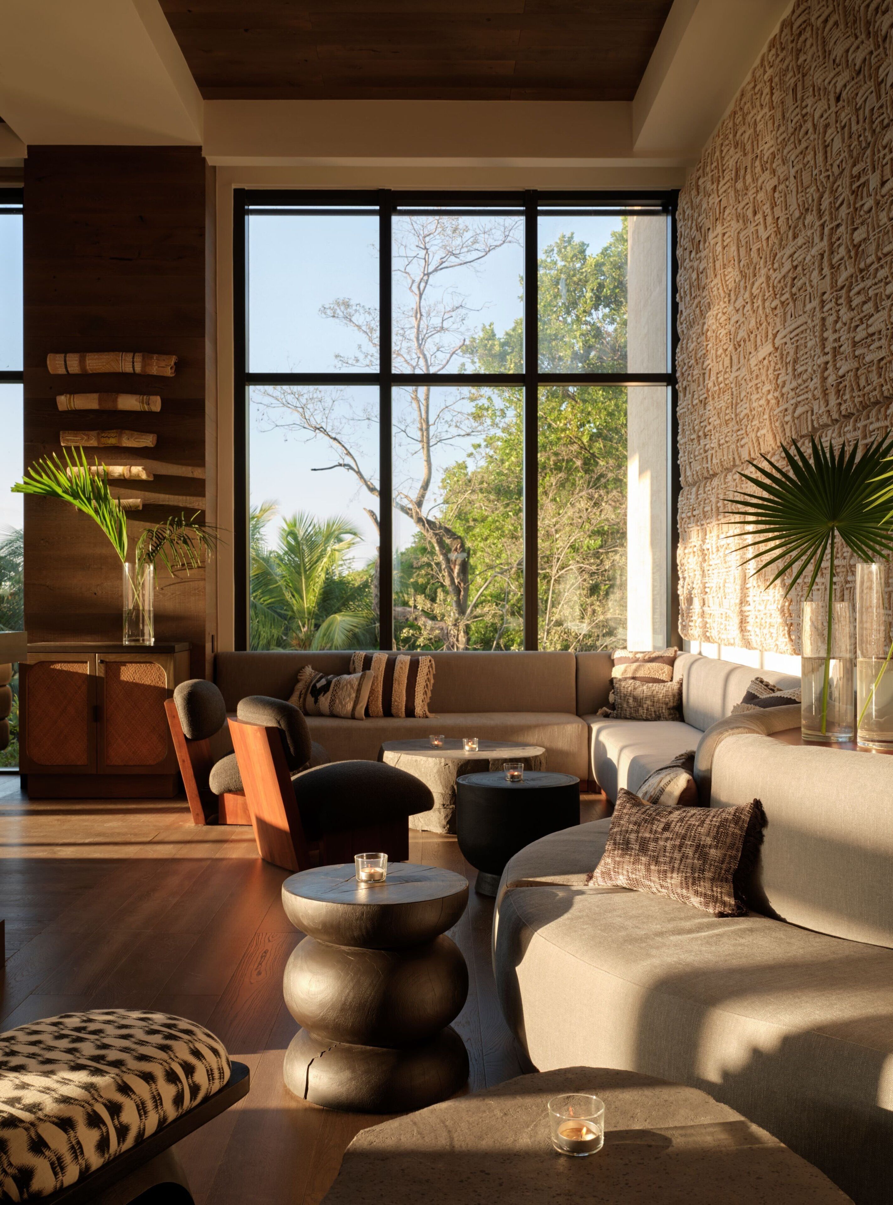 Un salón moderno con un ventanal grande, una pared de piedra y diversas opciones de asientos.