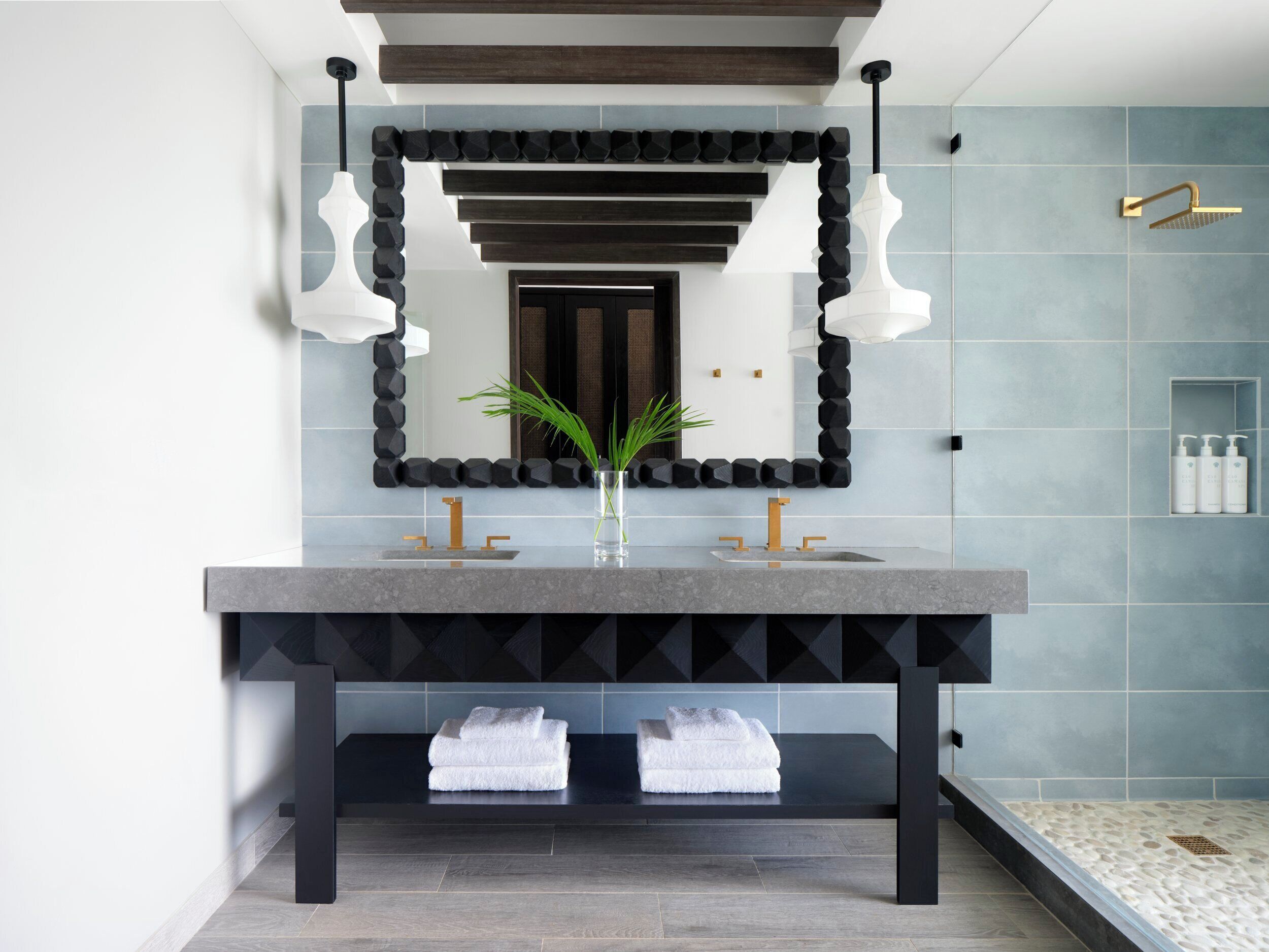 Un baño moderno con un espejo grande, dos lavamanos, un perchero y una zona de ducha.