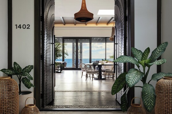 A modern hotel lobby with a dining area, large windows, and tropical plants. - Kimpton Grand Roatan Resort And Spa by IHG (Roatan)