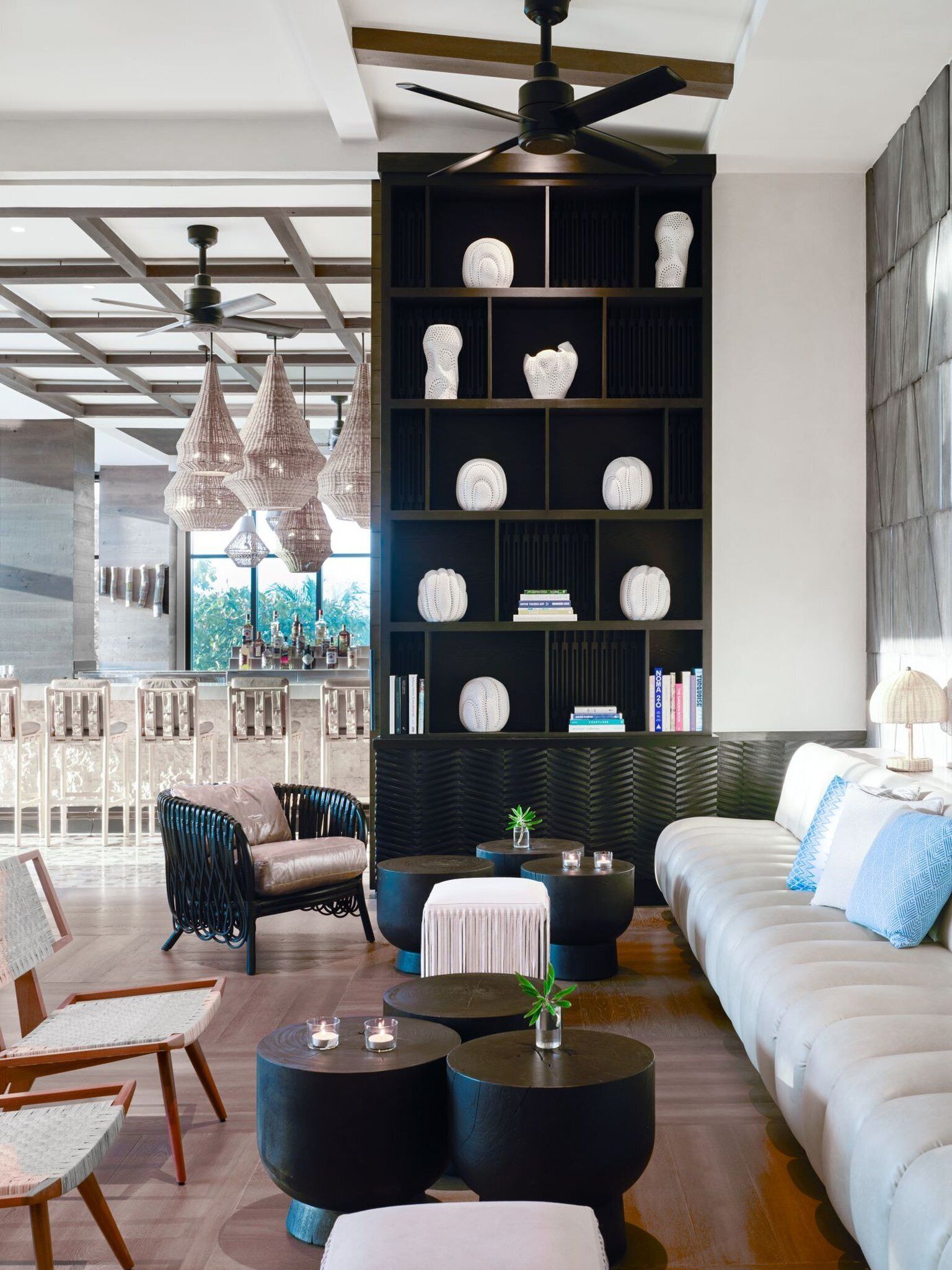 A modern living room with a sectional sofa, a bar area with bottles, and a bookshelf with decorative items.