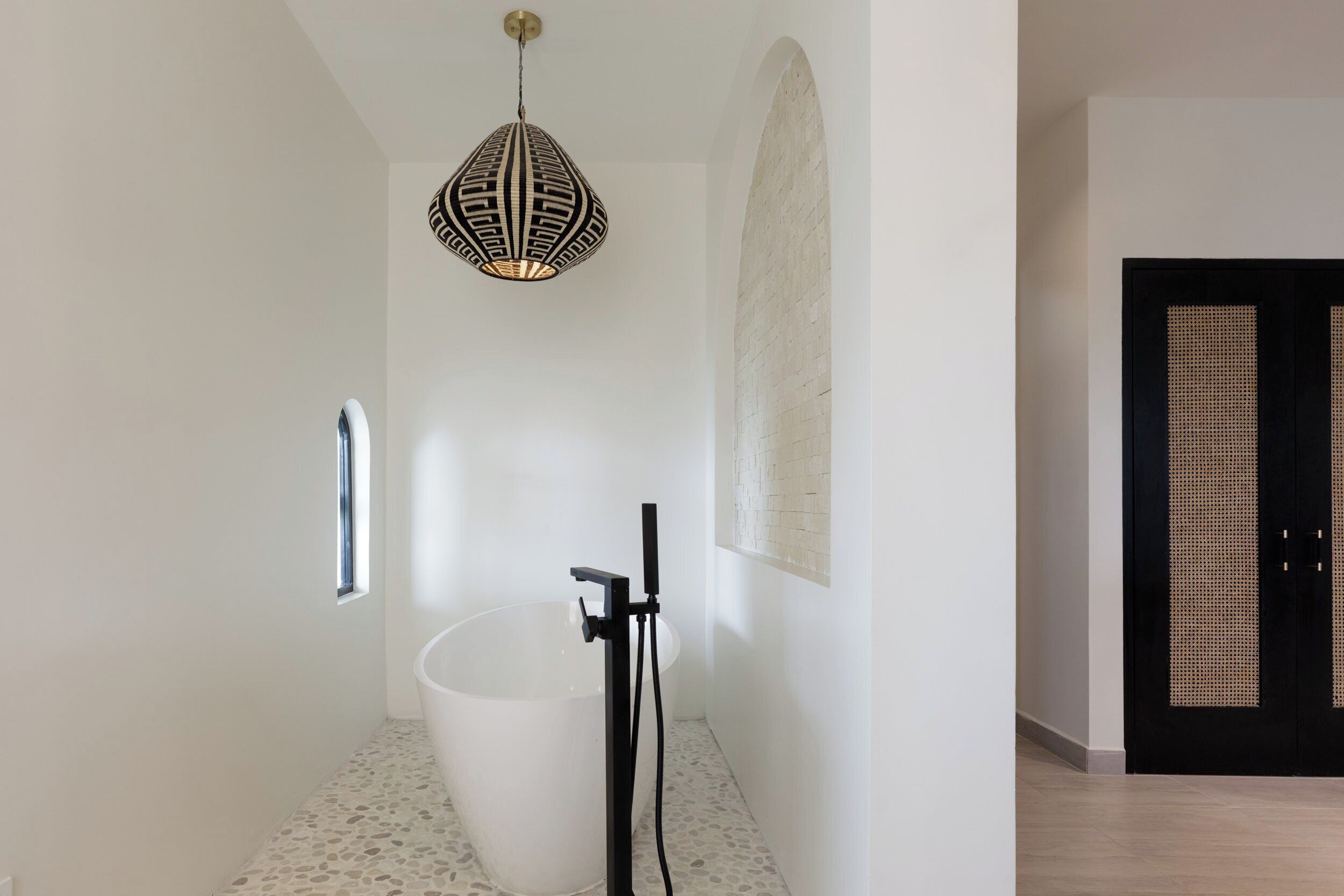 A bathroom with a freestanding bathtub, a pendant light, and a window.