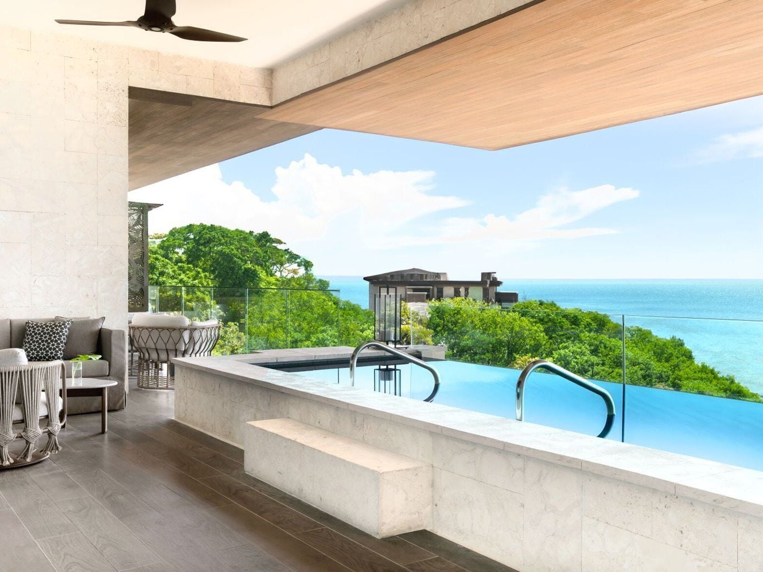 Une piscine à débordement moderne offrant une vue dégagée sur l’océan et un paysage verdoyant luxuriant.