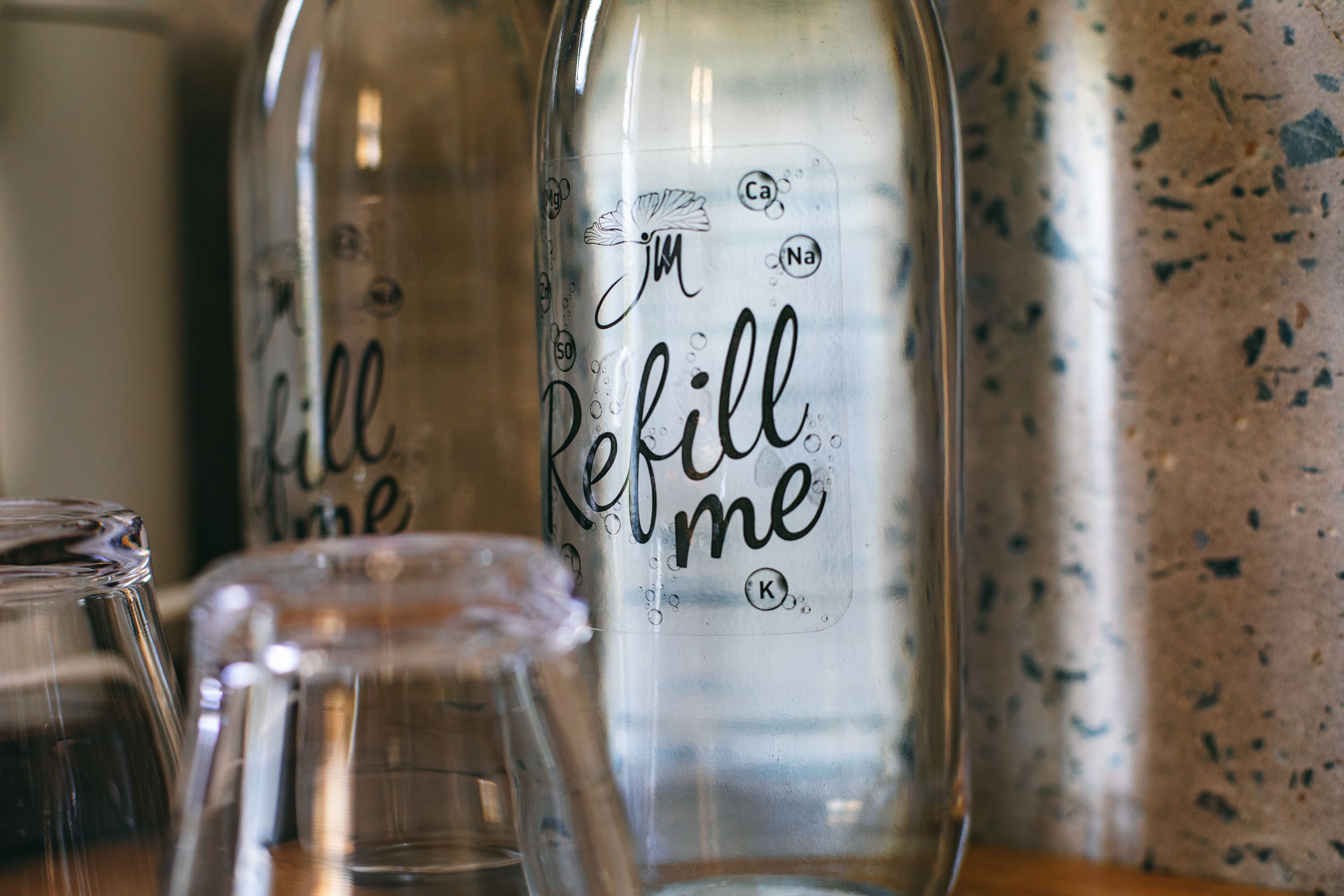 Three glass bottles with the text "Refill me" and chemical symbols on them.