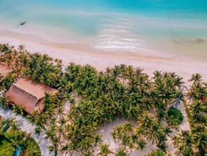 An aerial view of a beach with a thatched-roof building surrounded by palm trees. - JM Boutique Hotel (Phu Quoc)