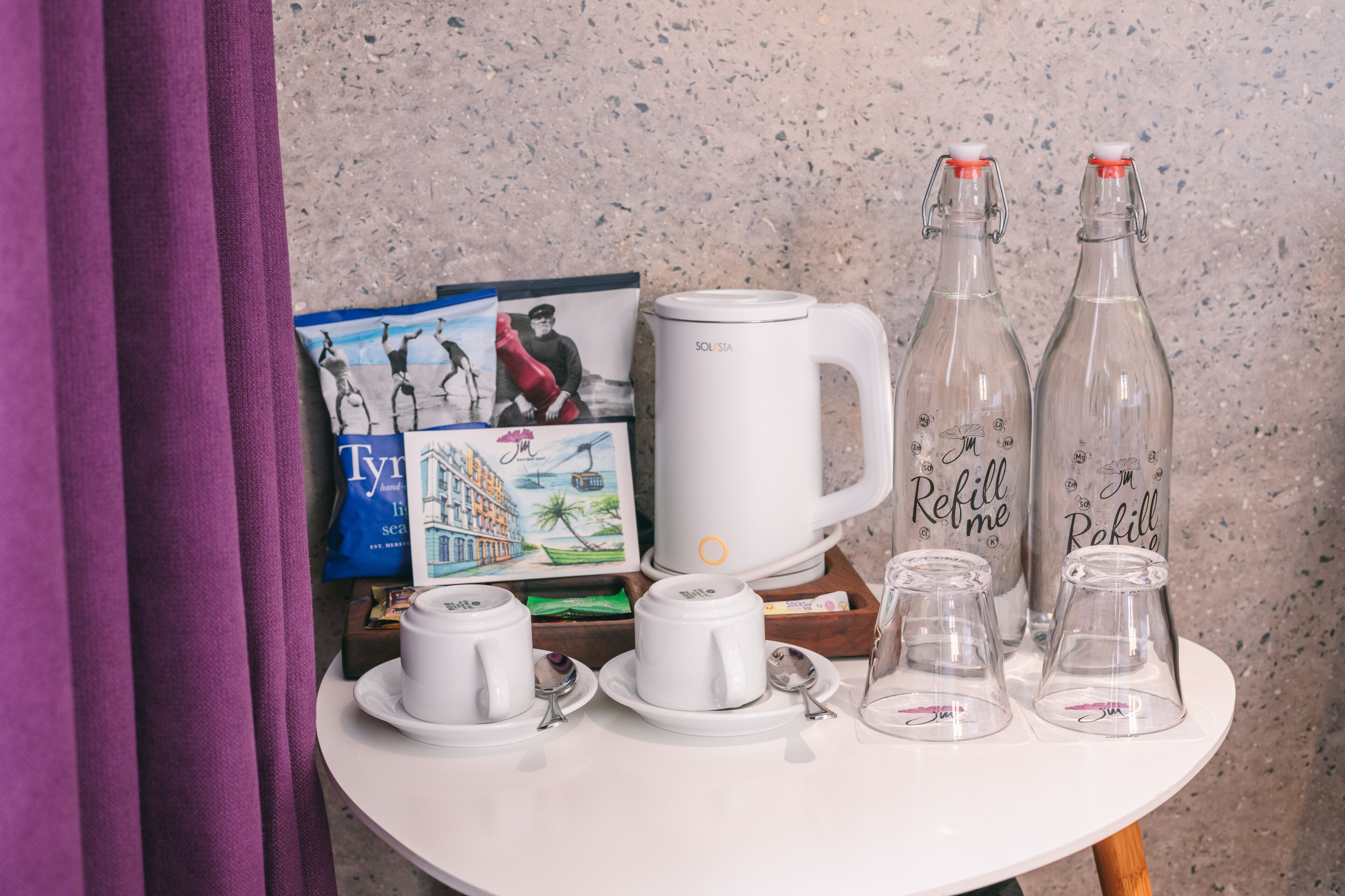 A table with a white mug, two glass bottles, and a white coffee pot.