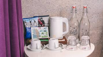 A table with a white mug, two glass bottles, and a white coffee pot.