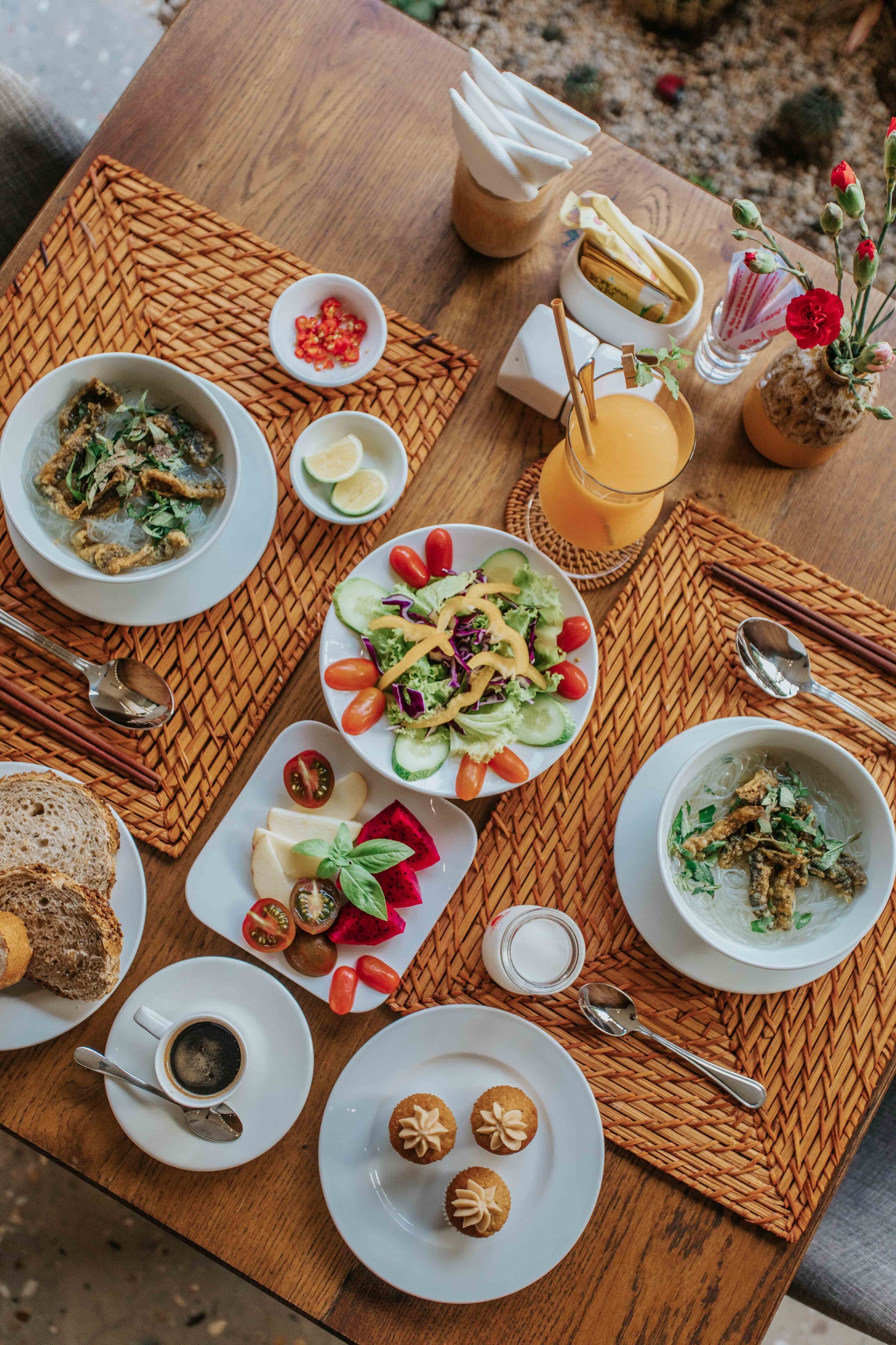 A table set with various dishes, including bowls of soup, a salad, and plates of fruit.