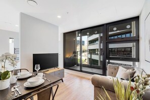Un salon moderne comprenant un coin repas, de grandes portes-fenêtres coulissantes, un téléviseur à écran plat et un canapé.