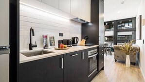 A modern kitchen with a black countertop, white backsplash, and a built-in oven. - CBD Modern Studio Apartment (Auckland)