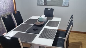 A dining area with a white table, black and white chairs, and a modern abstract painting on the wall. - *WI-FI & Netflix* Super Comfy Accom, 21meter Long  Boat Parking Available!! (Portland)