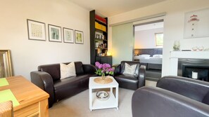 A living room with a black leather sofa, a white coffee table, and a bookshelf. - Haus Leuchtfeuer - Haus Leuchtfeuer - Bright vacation rental near the beach with (Cuxhaven)