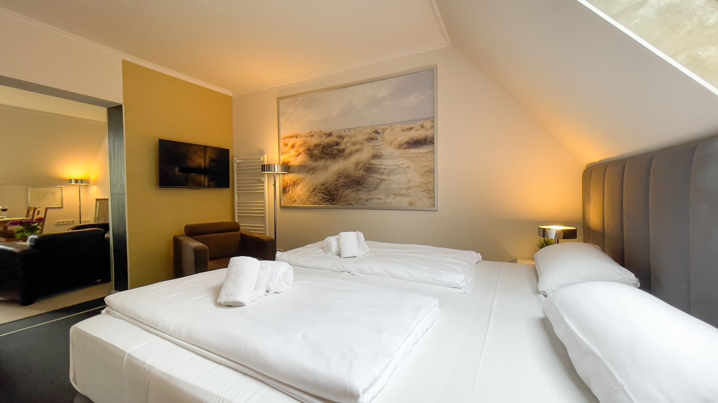 A hotel room with two beds, a large painting on the wall, and a desk with a chair.