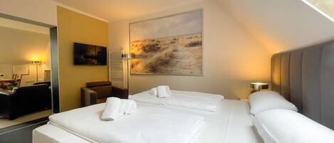 A hotel room with two beds, a large painting on the wall, and a desk with a chair.