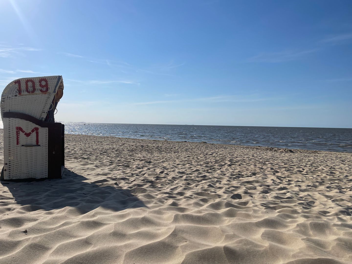 Ein Strand mit einem Stuhl, der mit '109 M' gekennzeichnet ist, und freiem Blick auf den Ozean.
