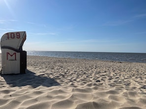Una playa con una silla marcada '109 M' y una vista despejada del océano.