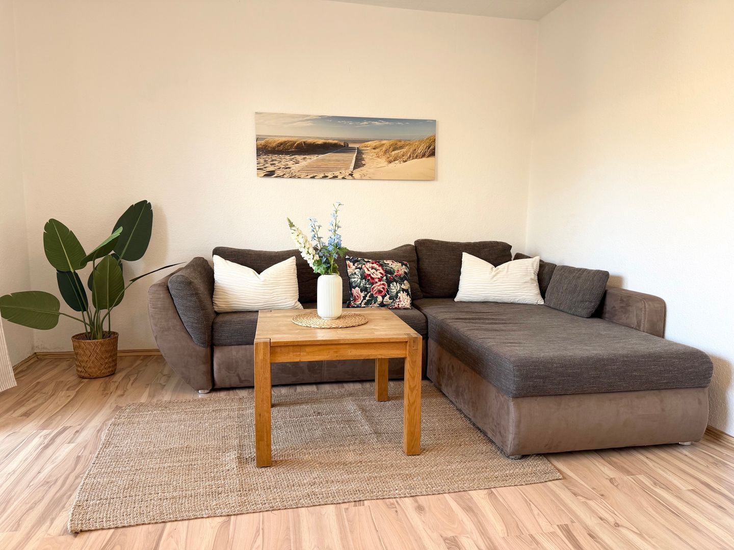 Una sala de estar moderna con un sofá modular, una mesa de centro de madera y una planta grande en maceta.