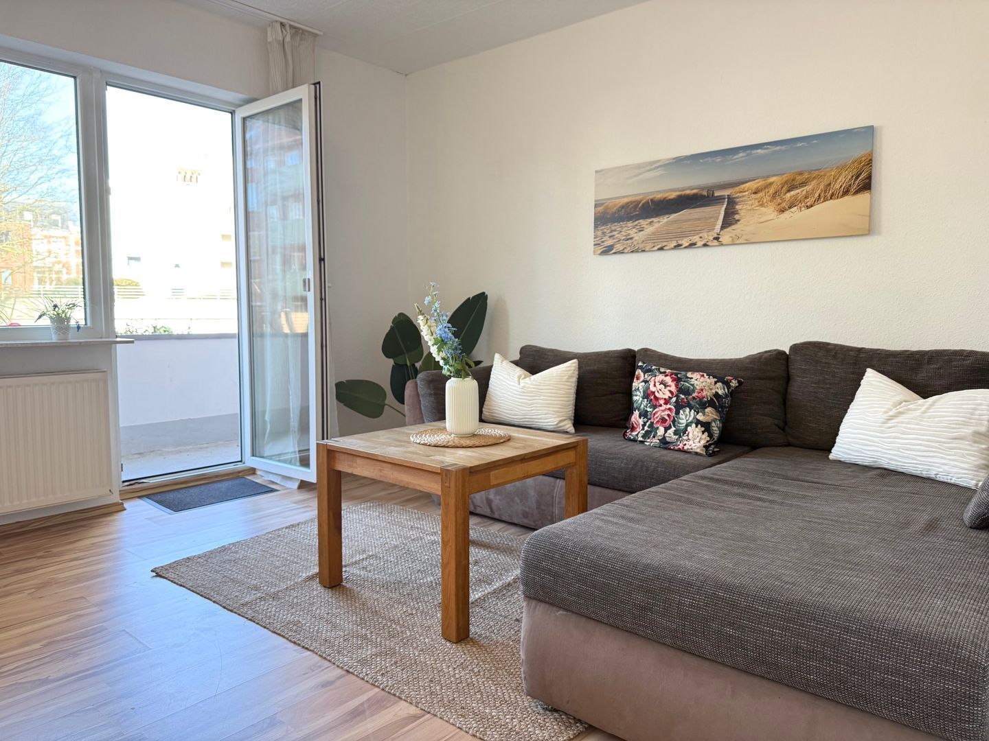 A modern living room with a sofa, a coffee table, and a painting on the wall.