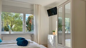 Una camera d'albergo con un letto, una TV fissata al muro, una finestra con vista sugli alberi e un armadio bianco.