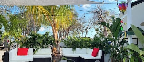 Uma área externa com mobiliário de vime e um toldo branco.