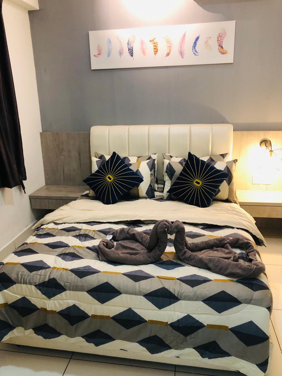 A bedroom with a bed, pillows, a wall art piece, and a nightstand.