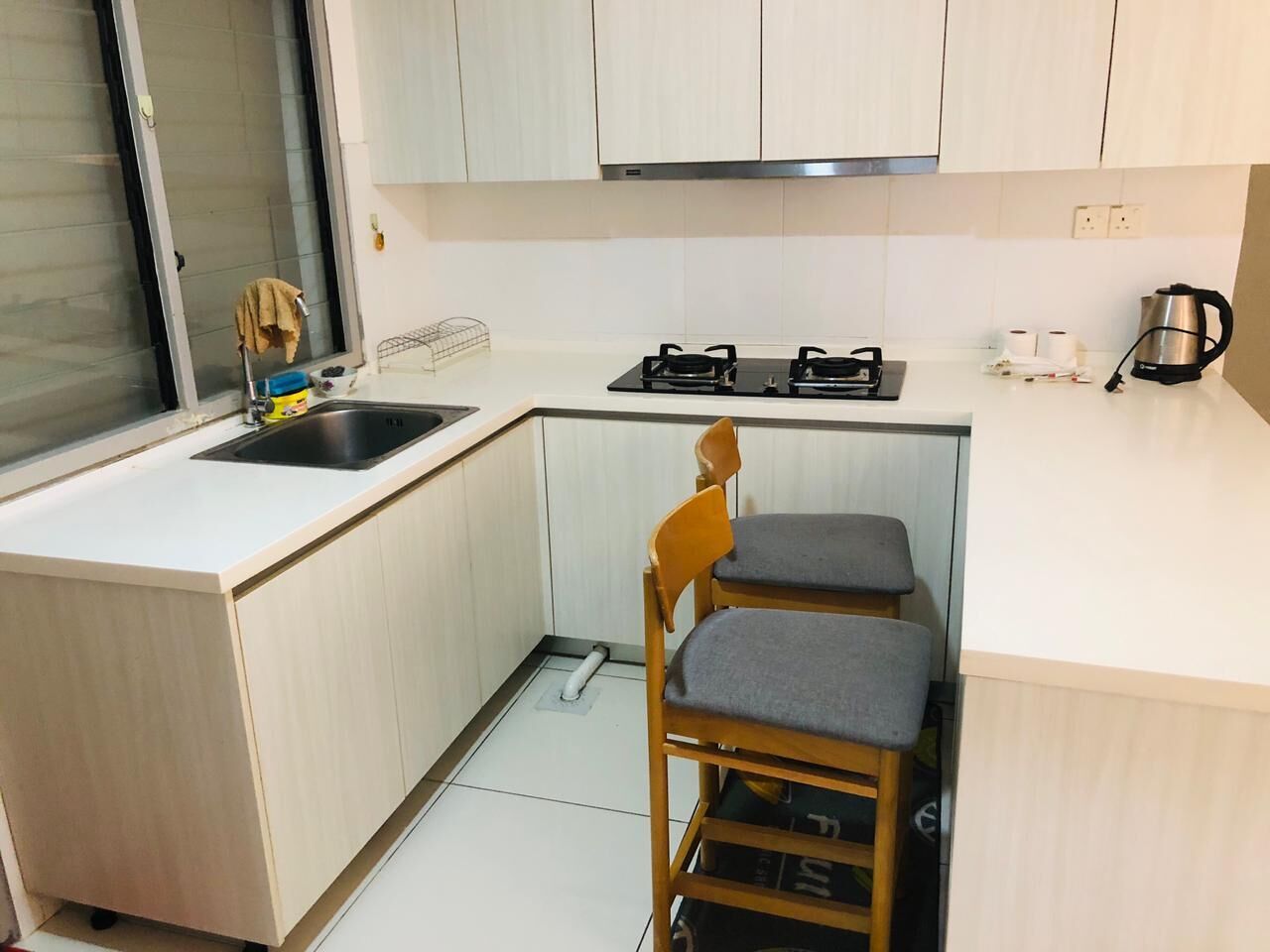 A compact kitchen with a sink, stove, and two wooden chairs.