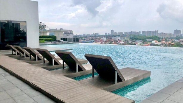 A pool area with lounge chairs and a view of a cityscape. - 1 Tebrau Residences by YML Home (Johor Bahru)