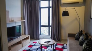 A modern living room with a flat-screen TV, a round coffee table, a sofa with decorative pillows, a floor lamp, and a large window with curtains. - 1 Tebrau Residences by YML Home (Johor Bahru)