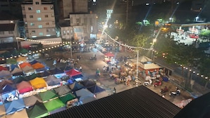 A nighttime outdoor market with tents and stalls, surrounded by buildings and streetlights. - W71  (Bangkok)