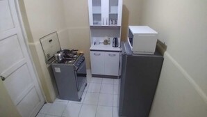 Una cocina compacta con estufa a gas, microondas y refrigerador.