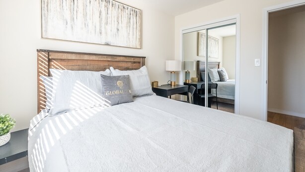 A neatly made bed with a headboard, a bedside table with a lamp, and a large mirror on the wall. - GLOBALSTAY. New 3BR 2.5BA Townhouse, 19km to Niagara Jorney (Thorold/Canada)