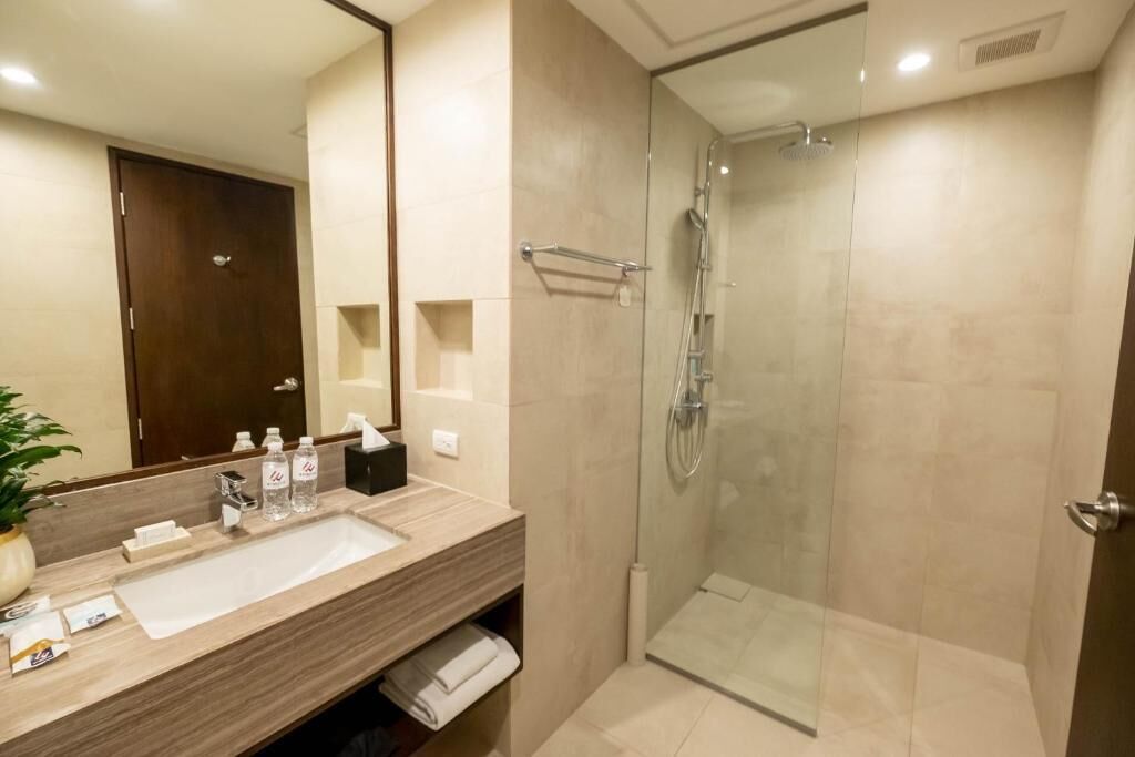 Une salle de bain moderne avec un grand miroir, un lavabo et une douche à parois de verre.