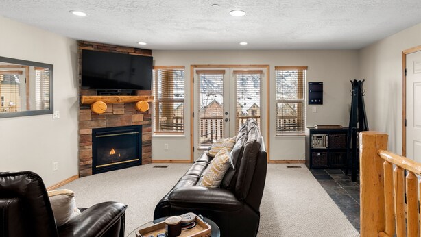 Una sala de estar con chimenea, sofá de cuero y televisor.