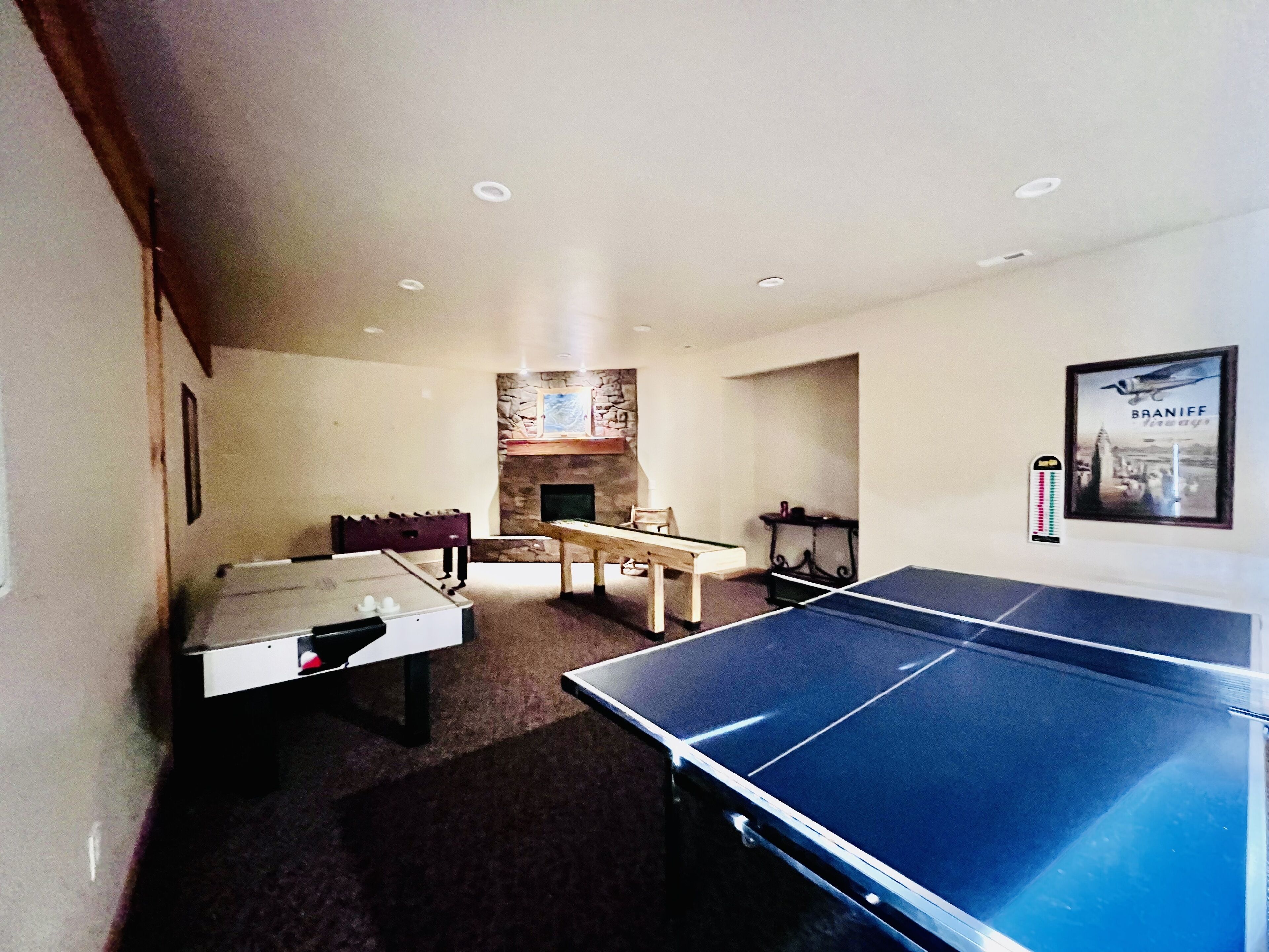 Una habitación con mesa de ping pong, chimenea y pared de piedra.