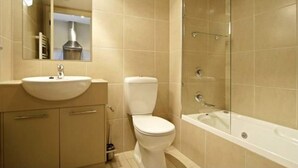 Une salle de bain équipée d’un lavabo, de toilettes et d’une douche à parois de verre.