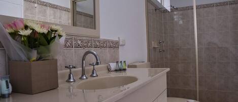 A bathroom with a sink, mirror, and shower.