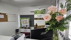 A reception desk with a remote control, a bulletin board, and promotional posters for agricultural tours. - Leeton Centre Motel (Leeton)