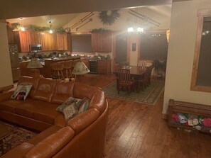 A spacious living room with a leather sofa, a dining area with wooden chairs, and a kitchen with wooden cabinets and a microwave. - Amazing View Mountain Home - Private Neighborhood (Silverthorne)