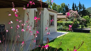 Une maison avec un jardin, une pelouse et un ciel bleu dégagé.