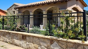 Une maison avec un toit en tuiles, des murs en pierre et une clôture en métal noir.