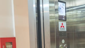 An elevator interior with a Mitsubishi sign, emergency stop button, and floor indicator buttons. - Luxury Airport Hotel & Travel (Hanoi)