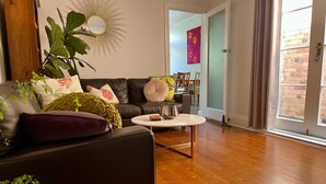 Uma sala de estar moderna com um sofá de couro, uma mesa de centro redonda e uma grande planta em vaso.