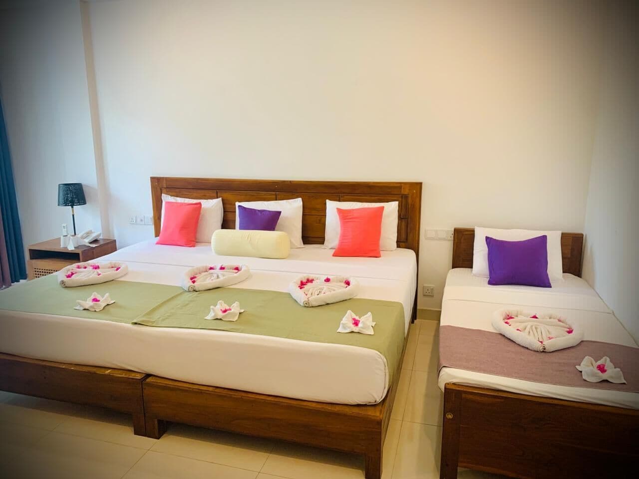 A double bed with a wooden headboard, two bedside tables, and a green bedspread.