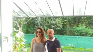 A couple standing in a covered outdoor area with a green fence and potted plants in the background. - Eden Grand (Dambulla)