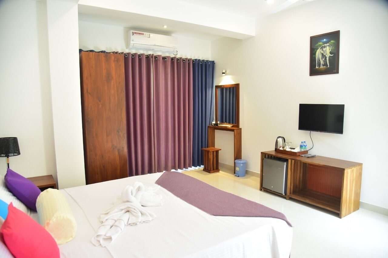 A hotel room with a bed, a television, a small cabinet, and a picture on the wall.
