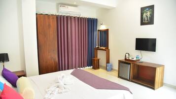 A hotel room with a bed, a television, a small cabinet, and a picture on the wall.